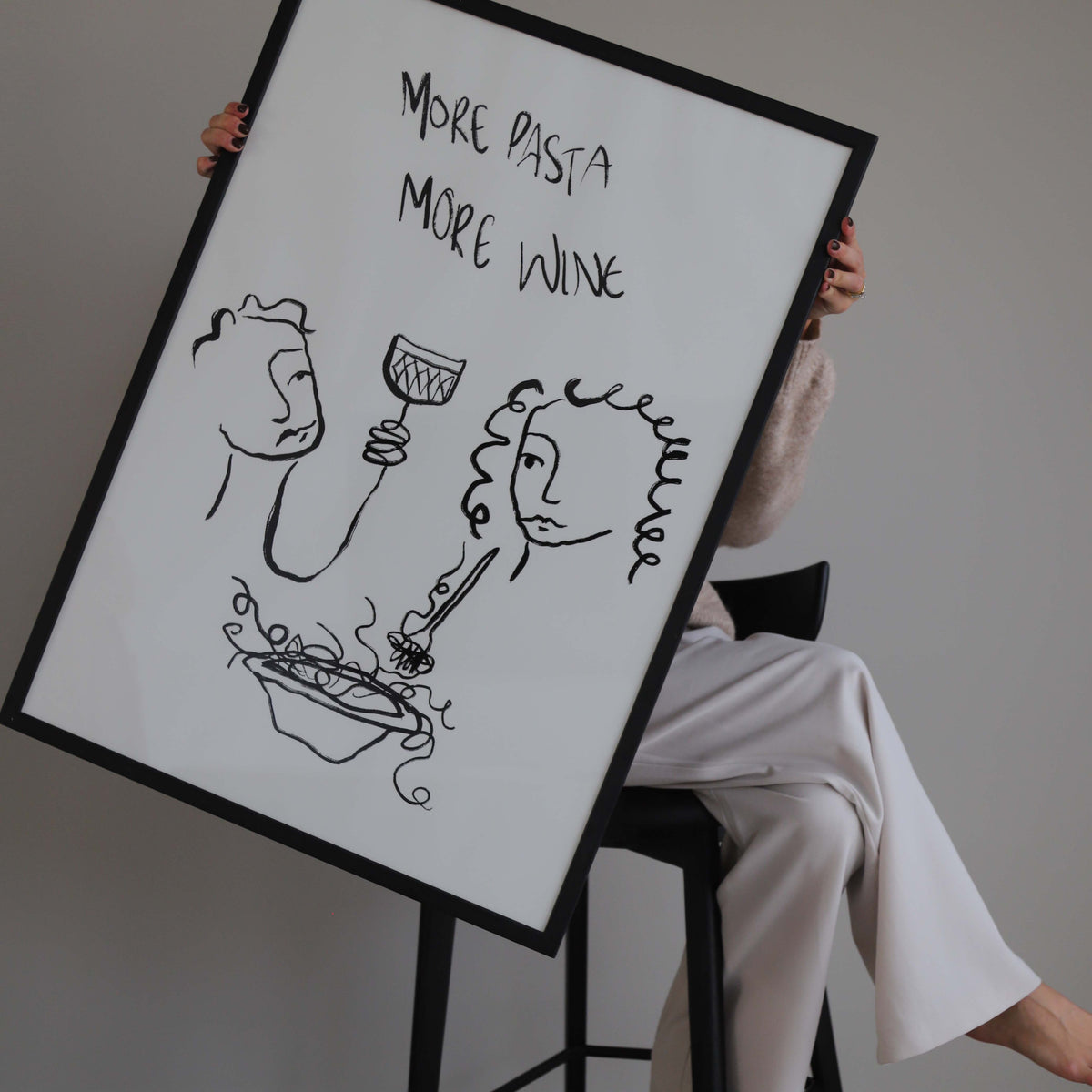 Person holding the More Pasta More Wine print in a black frame at an angle
