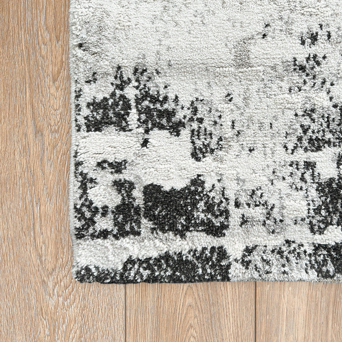 Corner of the distressed grey and black rug on a timber floor