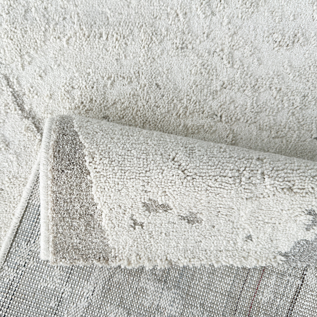 Grey and beige rug folded back to show its woven backing