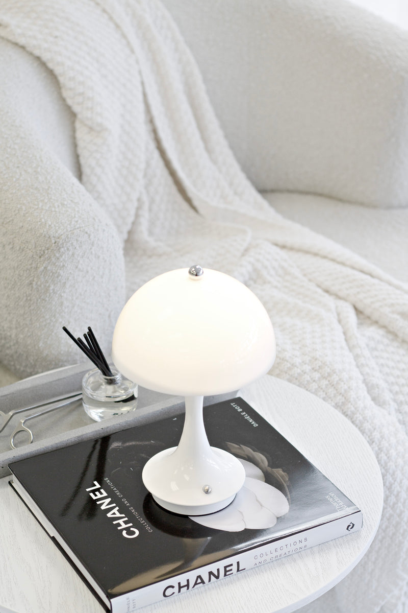 White lamp on a Chanel book with a diffuser and white blanket in the background