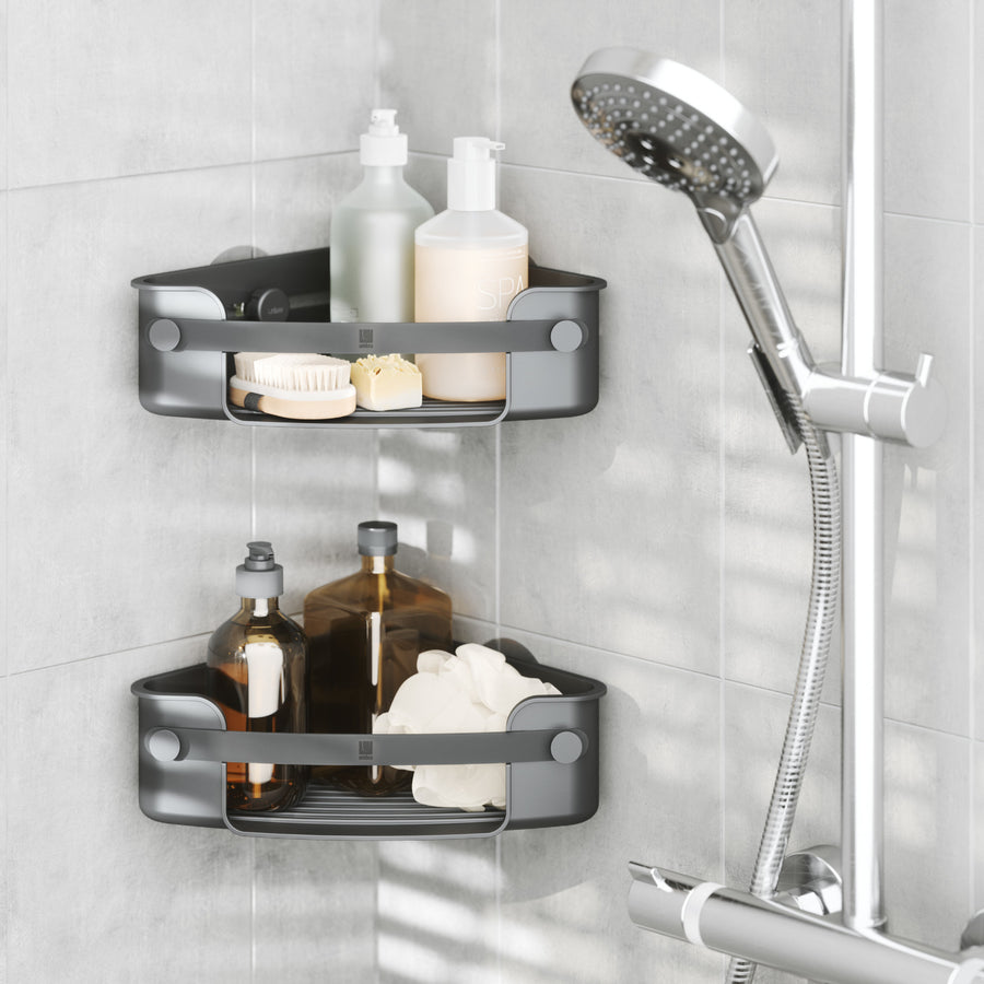 Two Umbra Flex corner bins in black in a tiled shower with bottles and soap