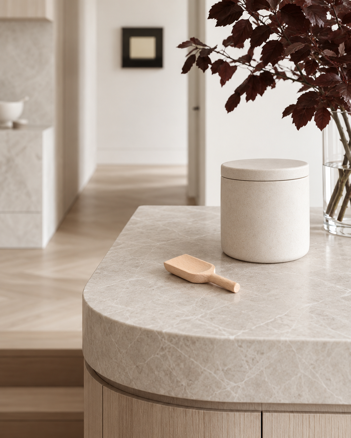 Wooden scoop beside a stone canister on a curved limestone kitchen island