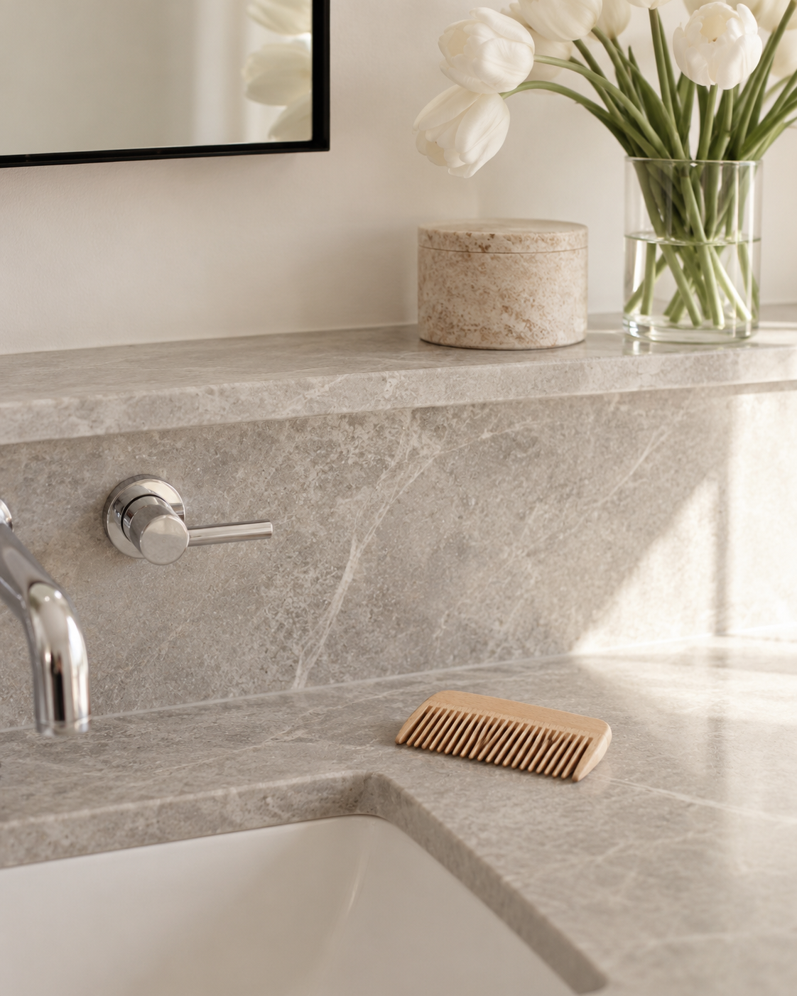 Wooden comb resting on a grey stone bathroom vanity beside the basin