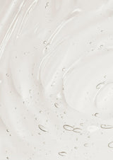Close-up texture of clear creamy hand and body wash with tiny air bubbles, swirled on a soft white background.