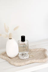 Ned Collections Harmie Vase in Pipi White ceramic, styled with dried bunny tails and perfume on travertine tray