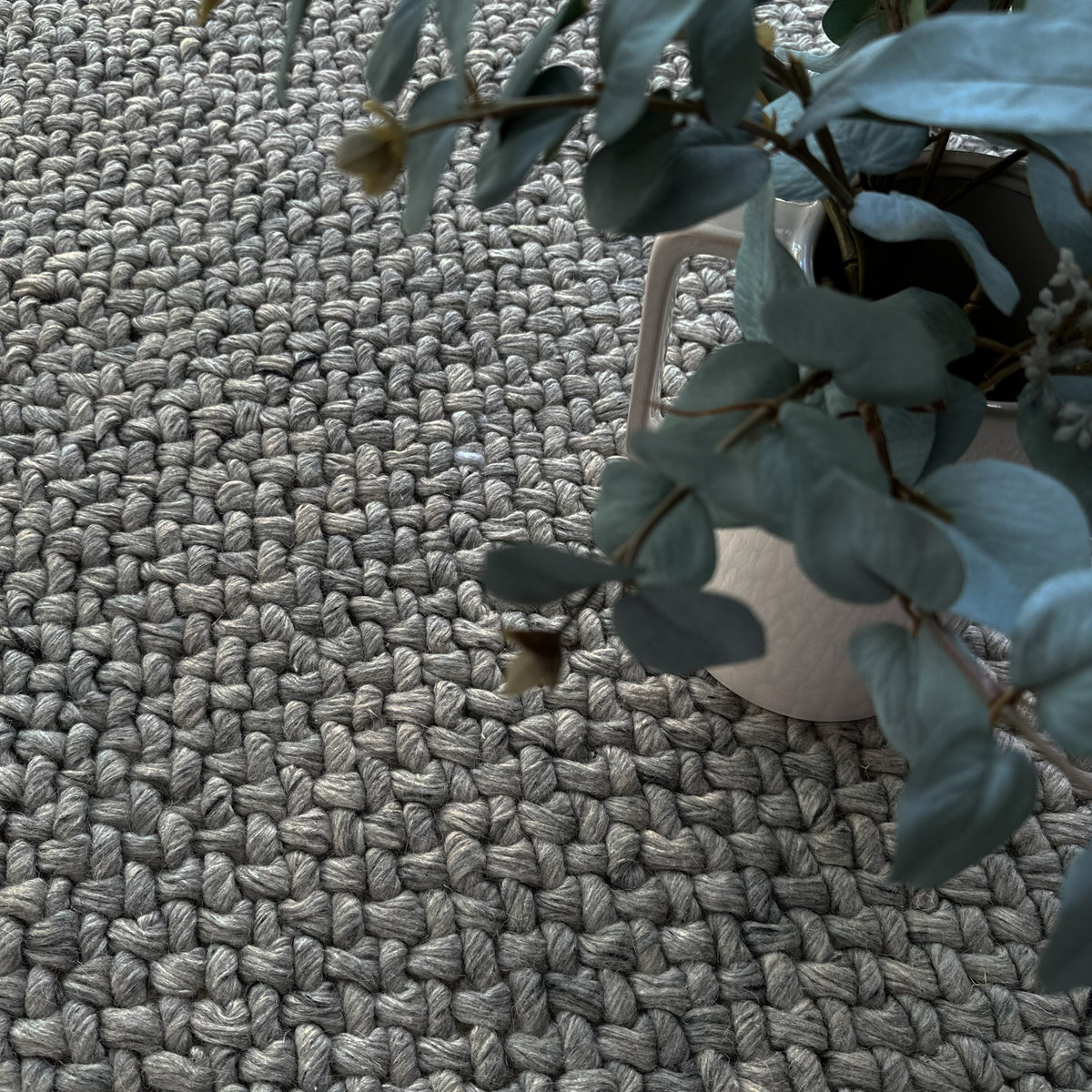 Chunky grey woven rug with potted eucalyptus on a white stool