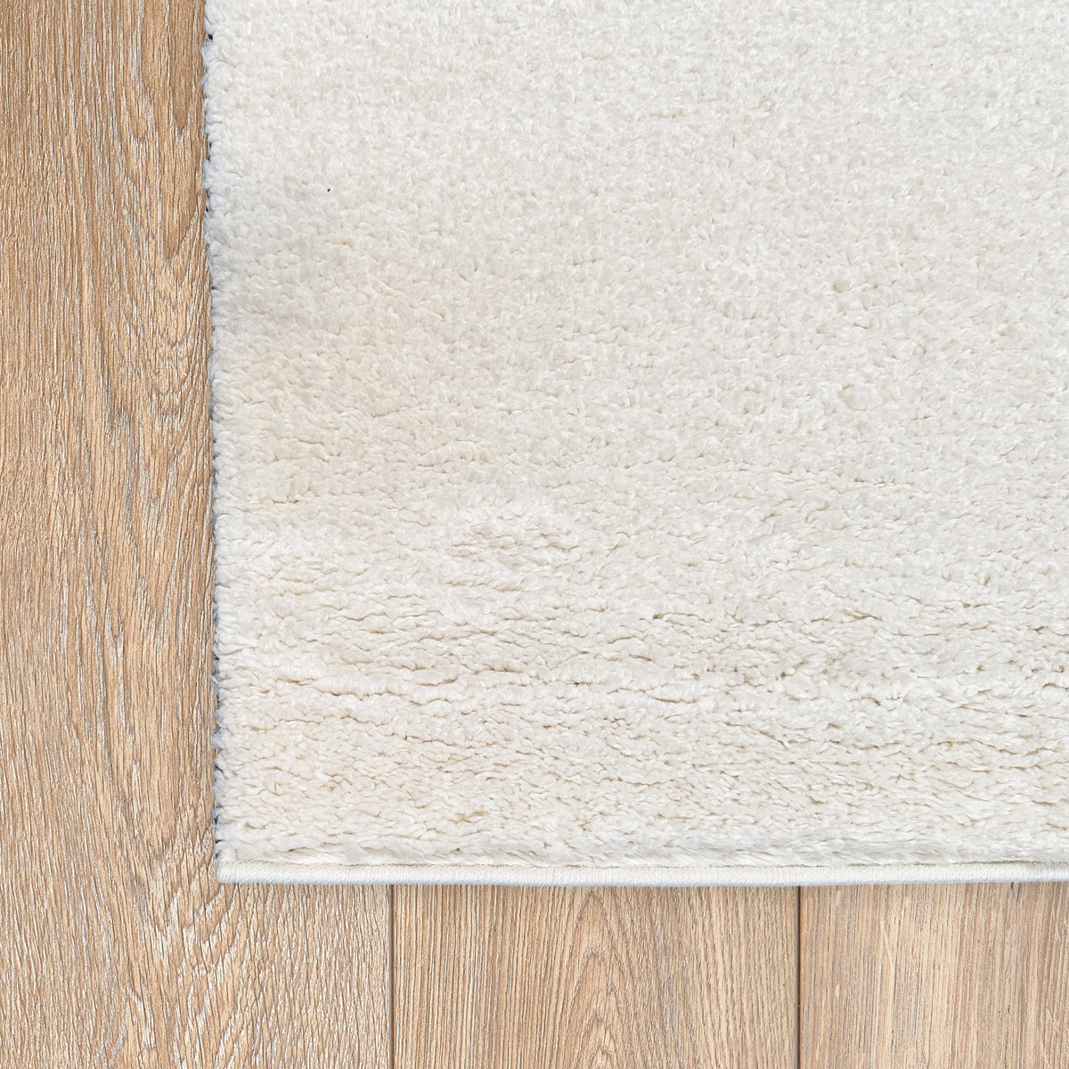 Corner of the chalk white rug on a light timber floor