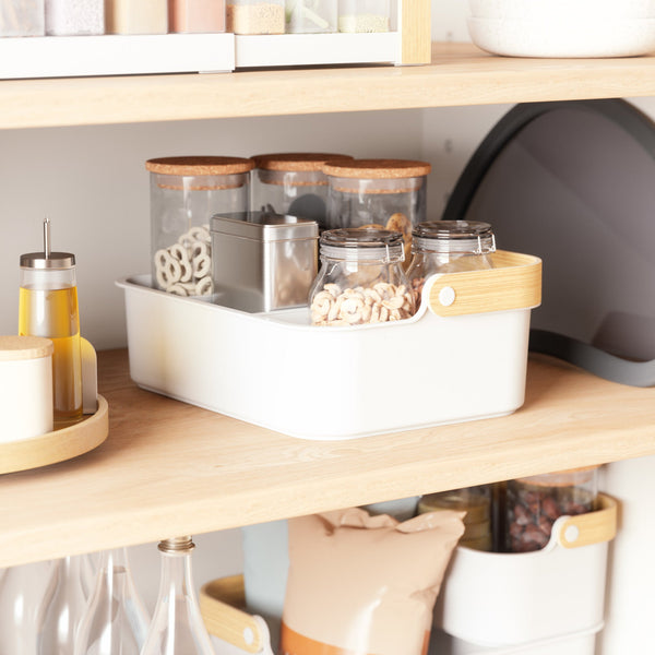 A white Umbra Bellwood Storage Bin with jars and other beauty station items on it, perfect for storing makeup.