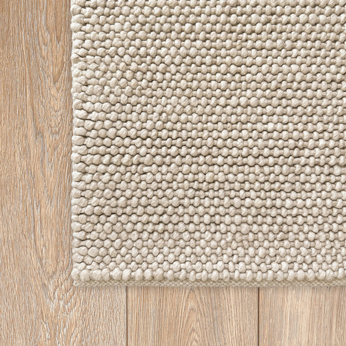 Corner of the beige loop rug on a timber floor