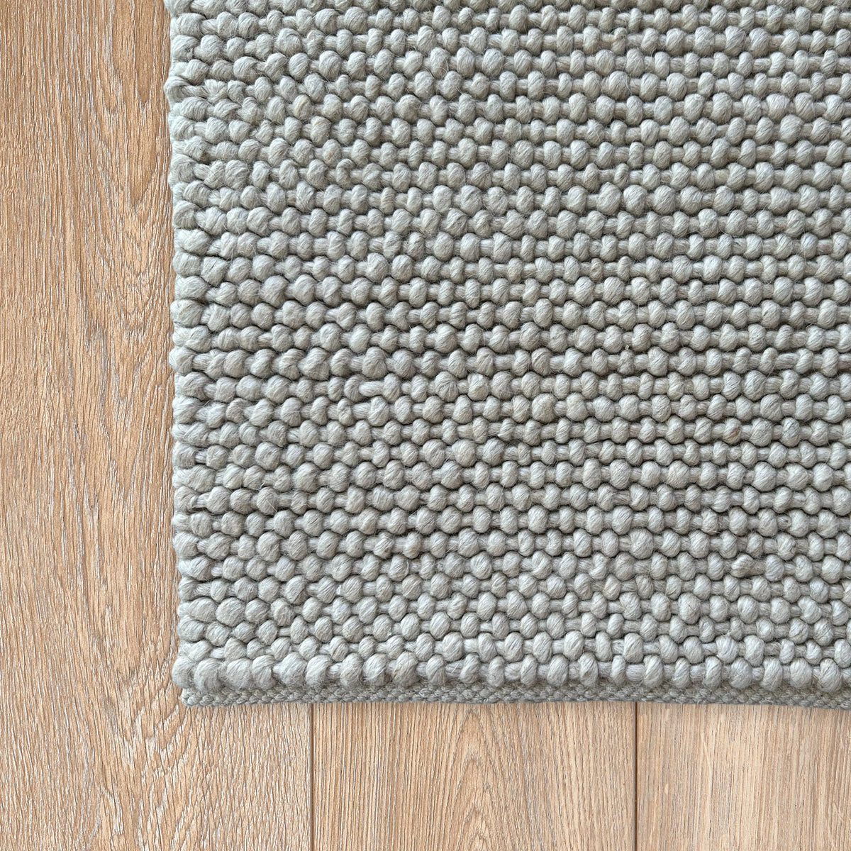 Corner of the grey loop rug on a warm timber floor