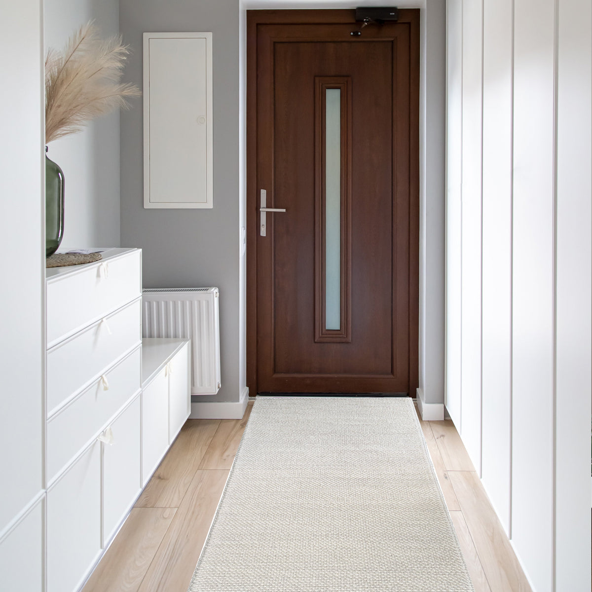 Ivory loop runner in a white hallway with built in cabinets leading to a timber front door