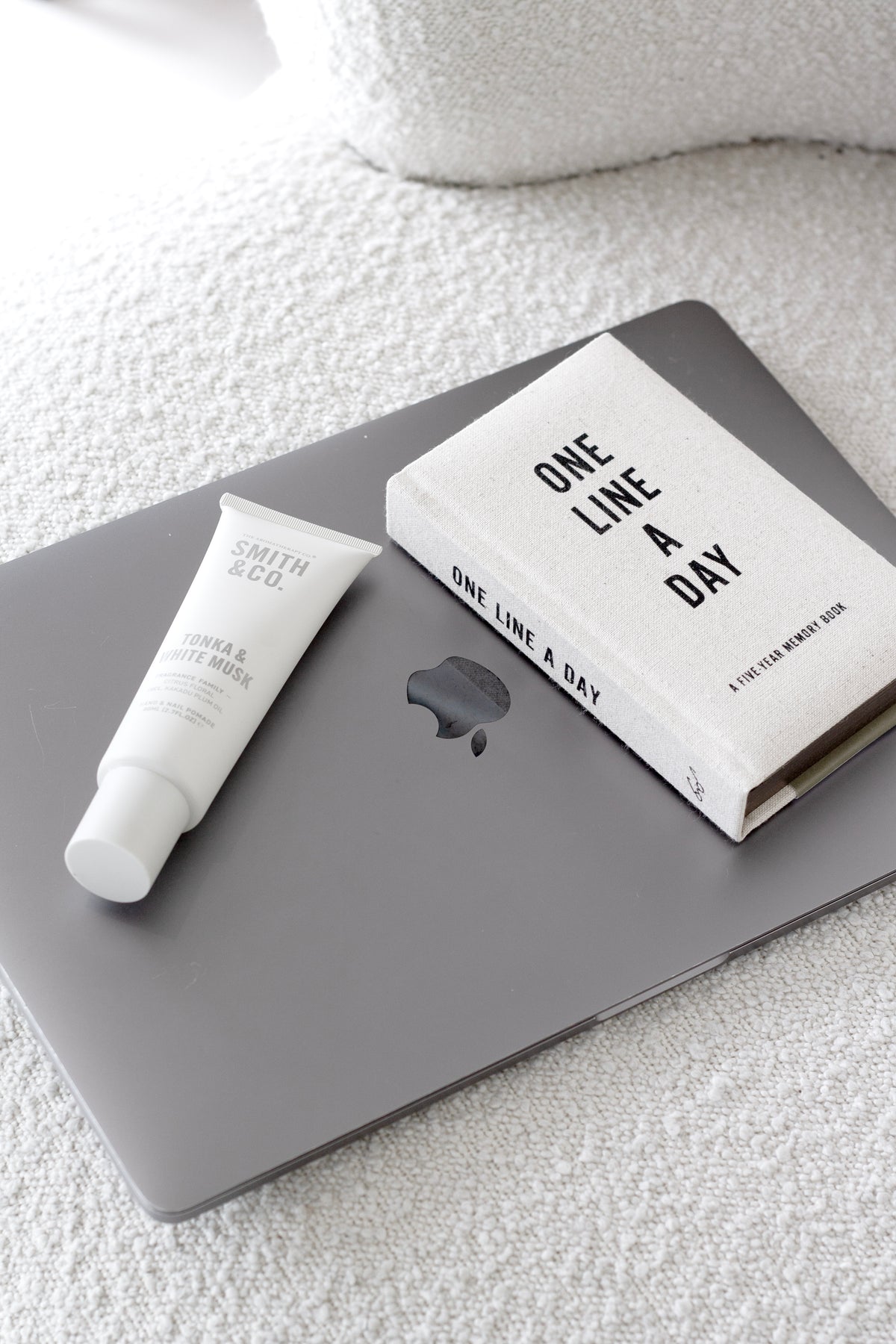 One Line a Day five-year memory journal styled on a laptop with Smith & Co hand cream on a boucle fabric background.