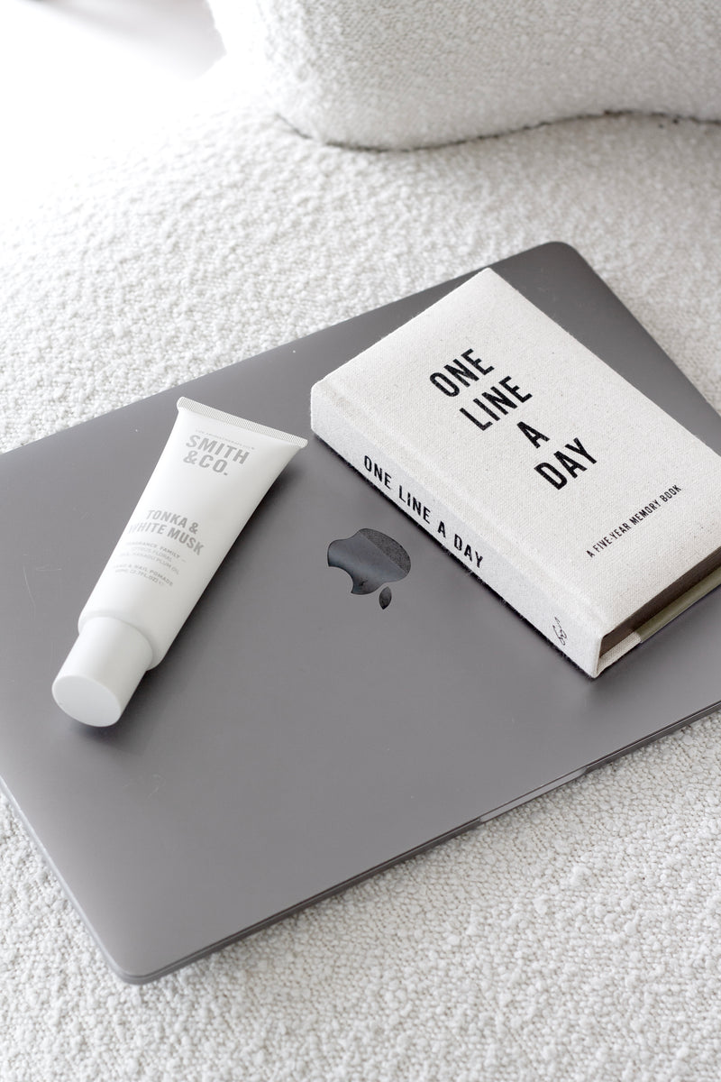 One Line a Day five-year memory journal styled on a laptop with Smith & Co hand cream on a boucle fabric background.