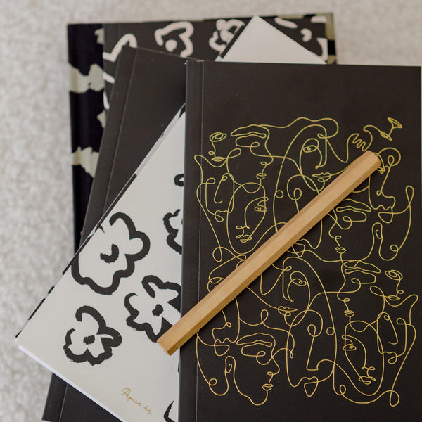 Stylish Papier HQ UNITY NOTEBOOKs with a pencil on top.