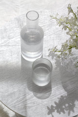 Papier HQ Amalfi fluted glass water decanter and tumbler on white oak table with white orchid blooms and shadow play