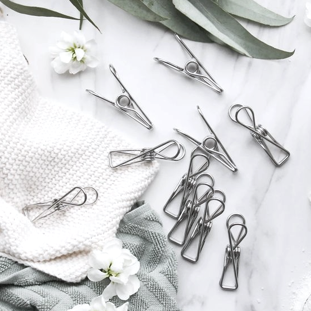 Stainless steel pegs scattered on white linen with eucalyptus and small flowers