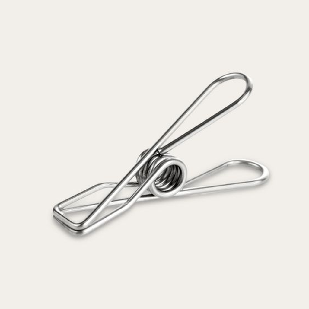 Single stainless steel clothes peg on a pale background, showing the coiled spring