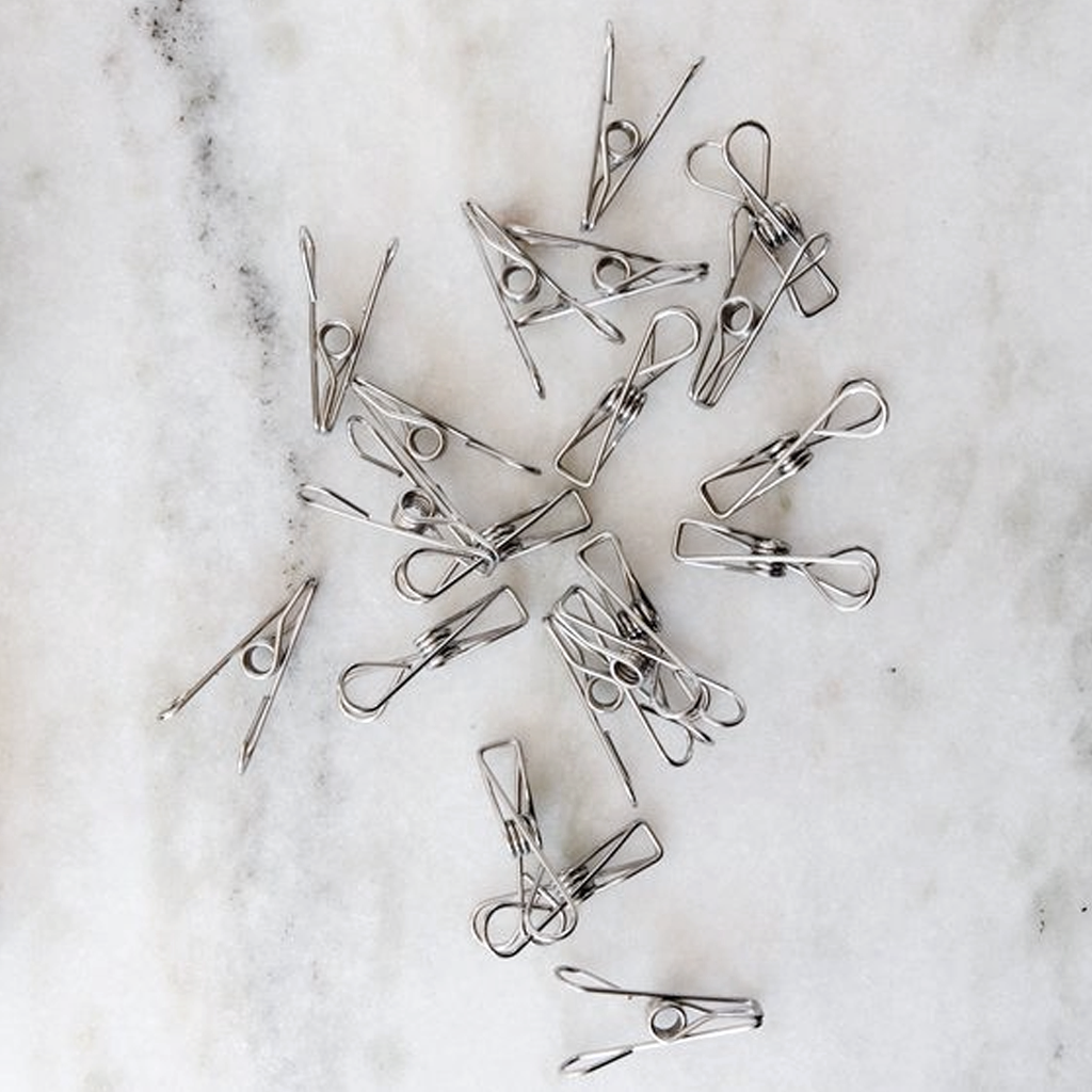 Stainless steel clothes pegs scattered across a marble surface