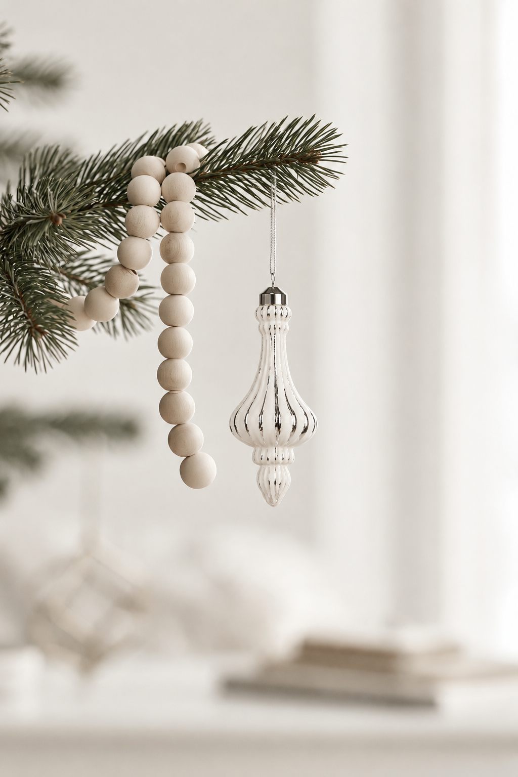 Pendant Bauble in white and silver 16.5cm hanging from a pine branch beside a wooden bead garland