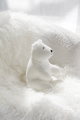 Peter Polar Bear soft toy in knitted white fabric styled on a fluffy cream chair in a cosy neutral space.