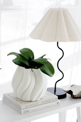 Phalaenopsis orchid leaf artificial spray with realistic wide green leaves, styled in a sculptural white vase on stacked design books.