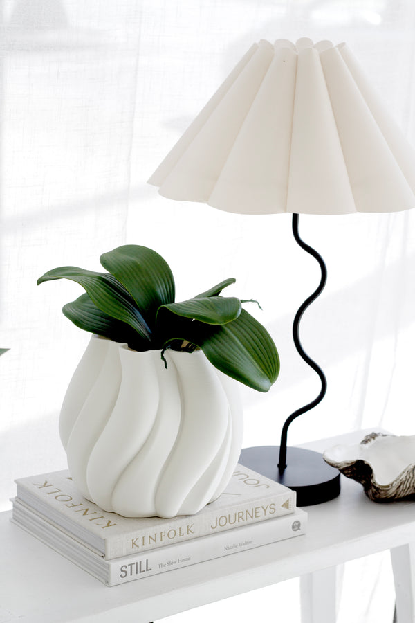 Phalaenopsis orchid leaf artificial spray with realistic wide green leaves, styled in a sculptural white vase on stacked design books.