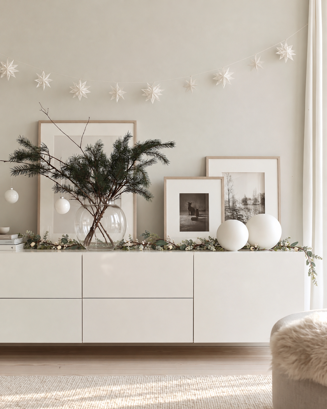 Podberry garland in cream draped along a white sideboard with framed prints and a vase of pine