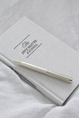 Gold luxe pen resting on linen journal minimalist desk styling