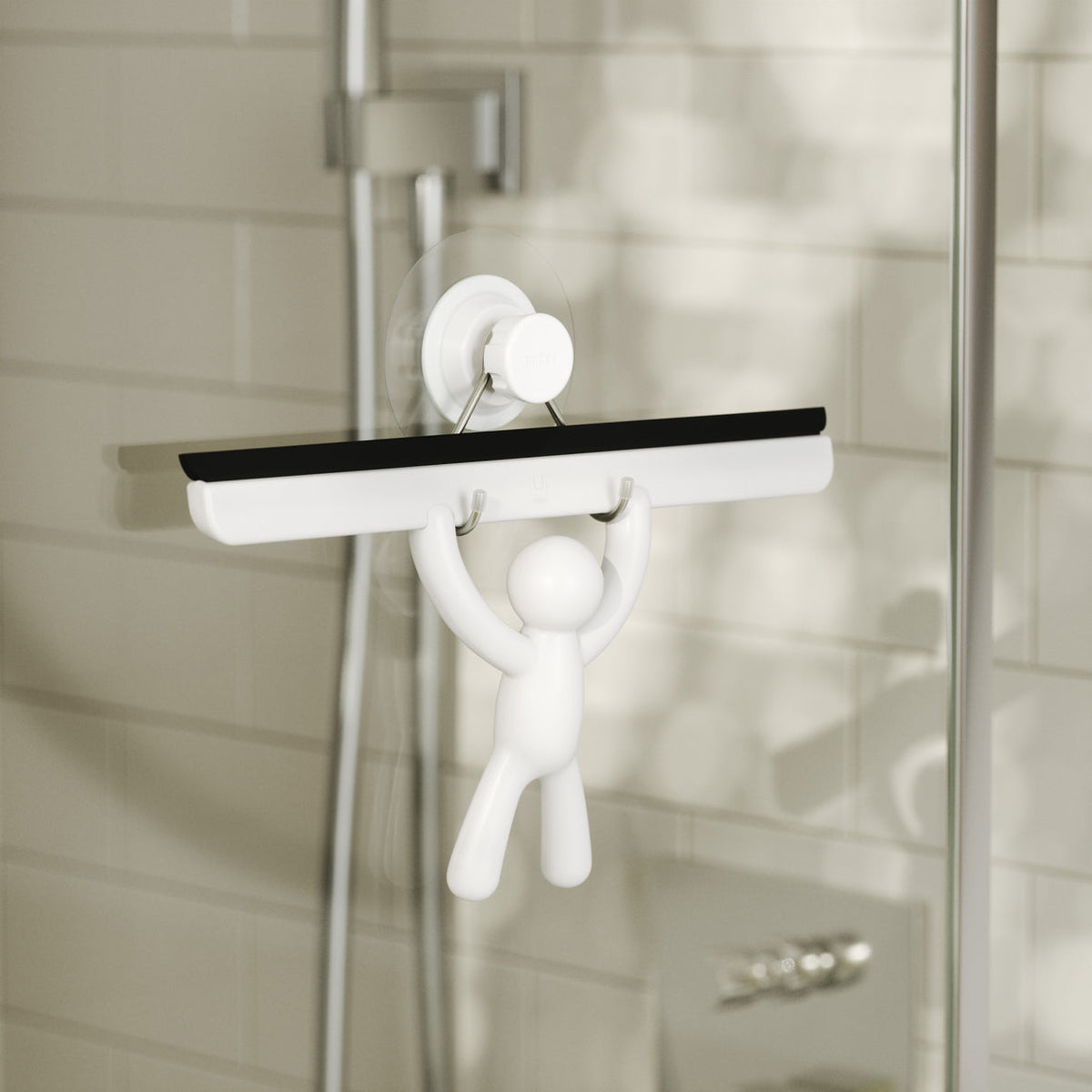 Umbra Buddy Squeegee in white mounted on a shower wall with its waterproof adhesive strip