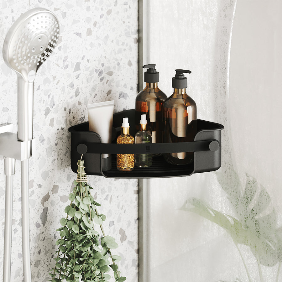 Umbra Flex adhesive corner bin in black holding bath bottles in a tiled shower corner