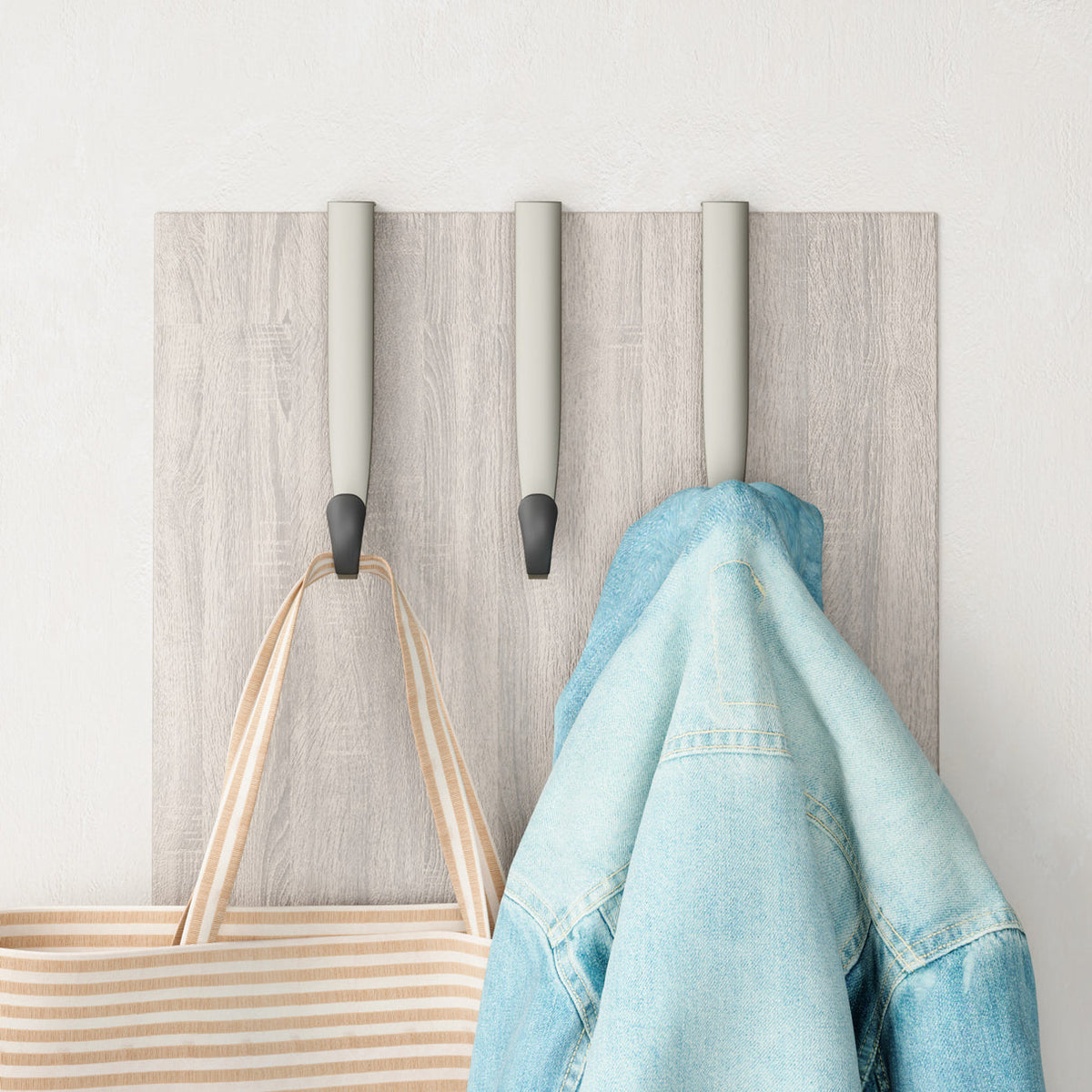 Umbra Schnook over-the-door hooks on a timber door holding a tote and denim jacket