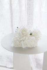 Real touch white faux rose bundle styled on round white table beside sheer curtains