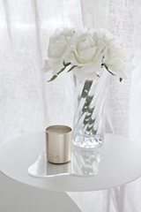 Real touch faux white roses arranged in clear glass vase on round side table