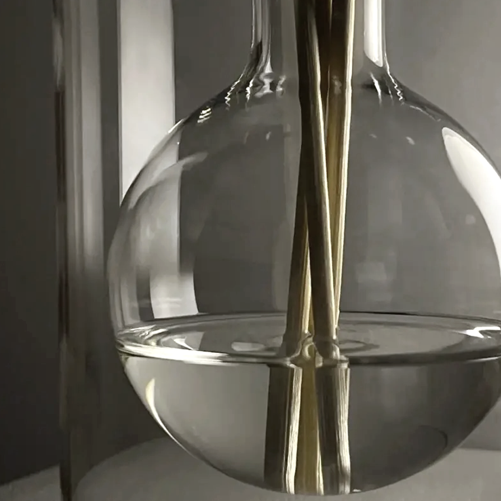 Close up of the glass reed diffuser showing the rounded inner reservoir and reeds