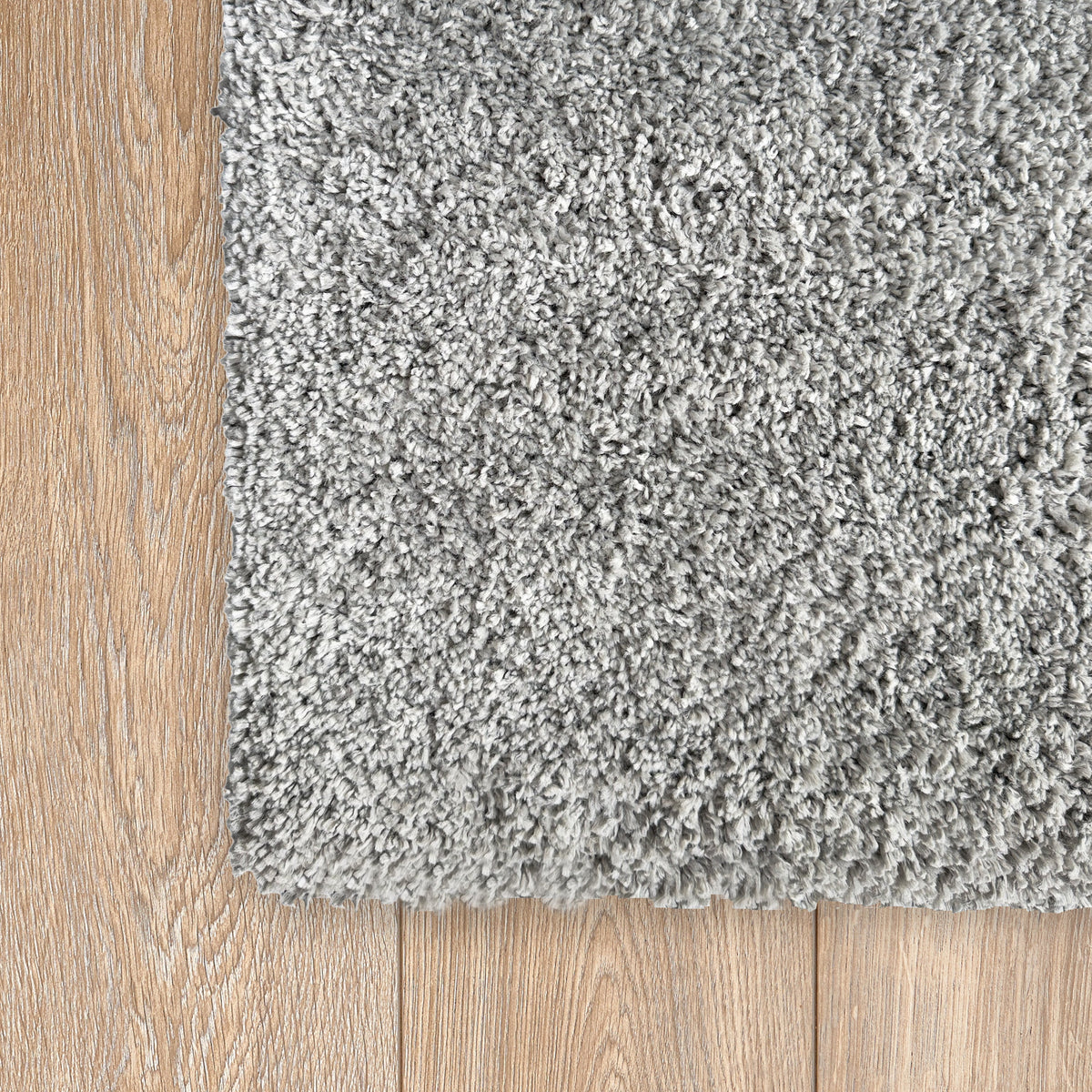 Corner of the grey plush rug on a light timber floor