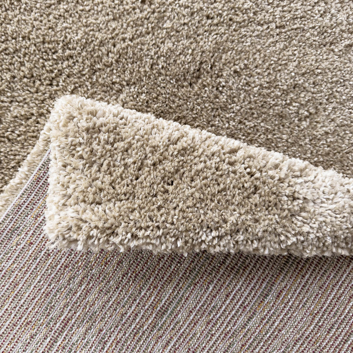 Folded corner of the oatmeal rug showing the pile and woven backing
