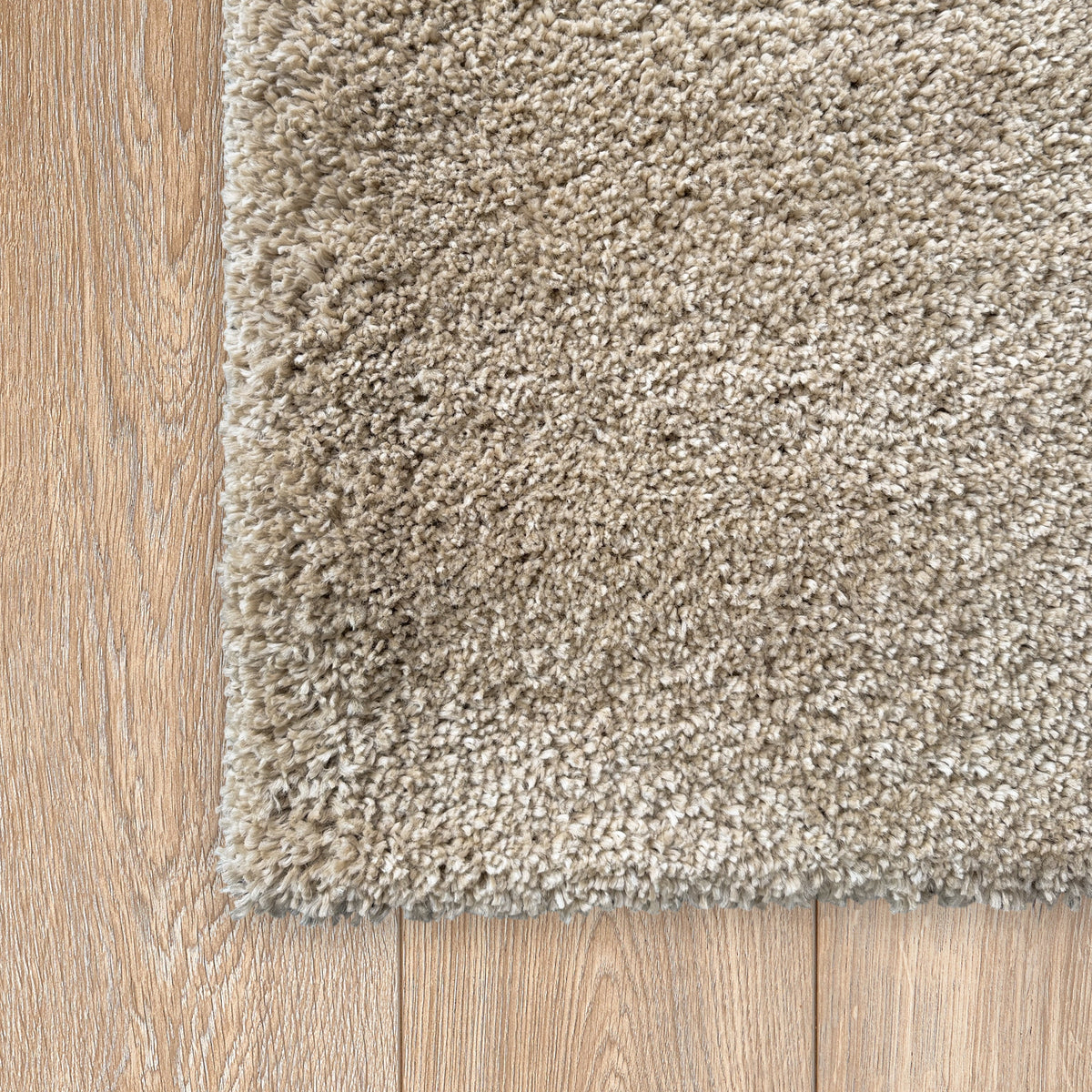 Corner of the oatmeal rug on a light timber floor