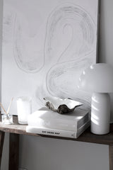 Resin clam shell bowl styled on books beside white table lamp in neutral coastal interior