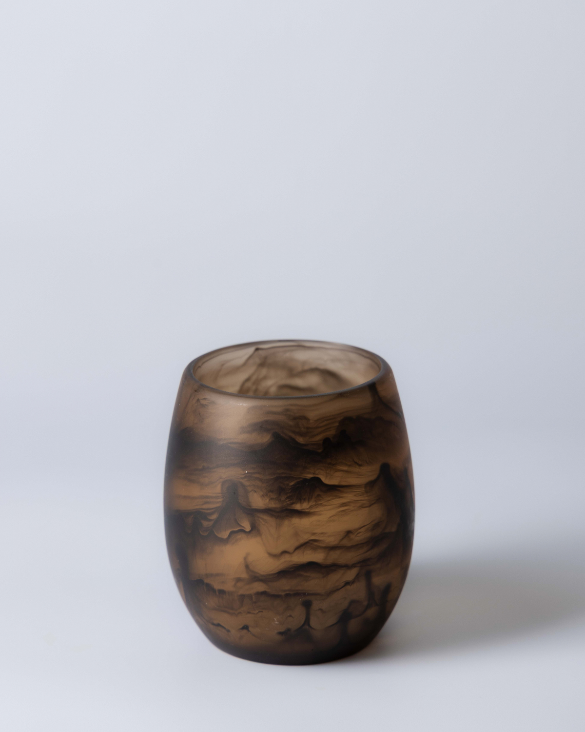Chocolate resin tumbler showing dark swirls through translucent brown resin against a soft blue backdrop