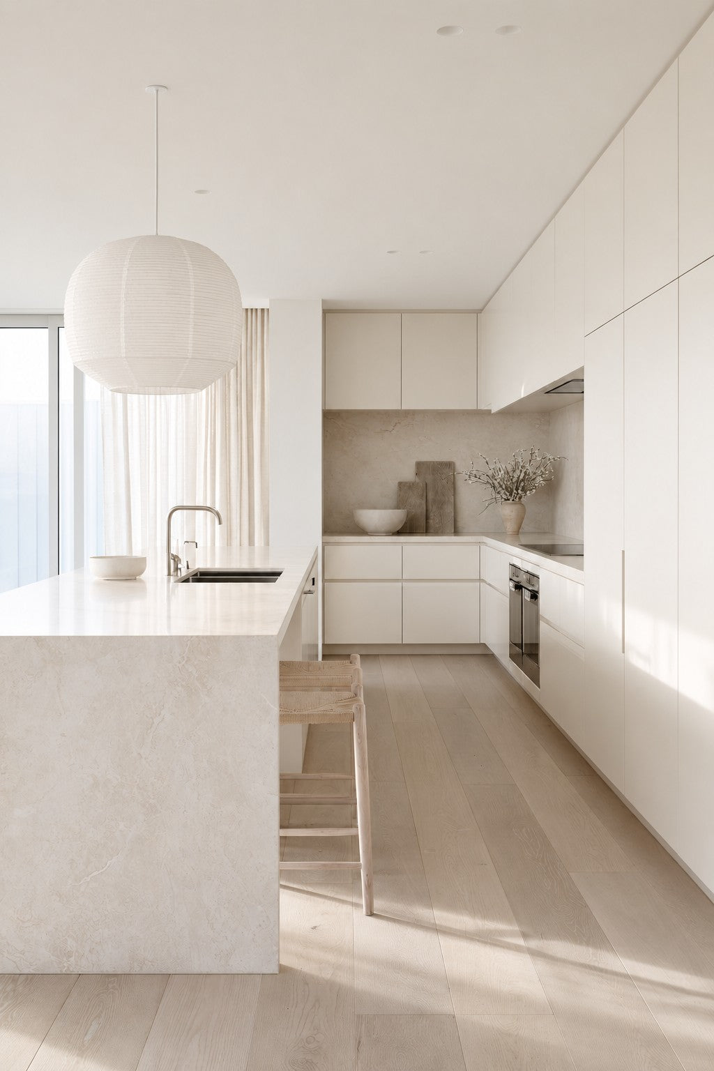 Rice paper pendant light hung low over a stone kitchen island with woven stools
