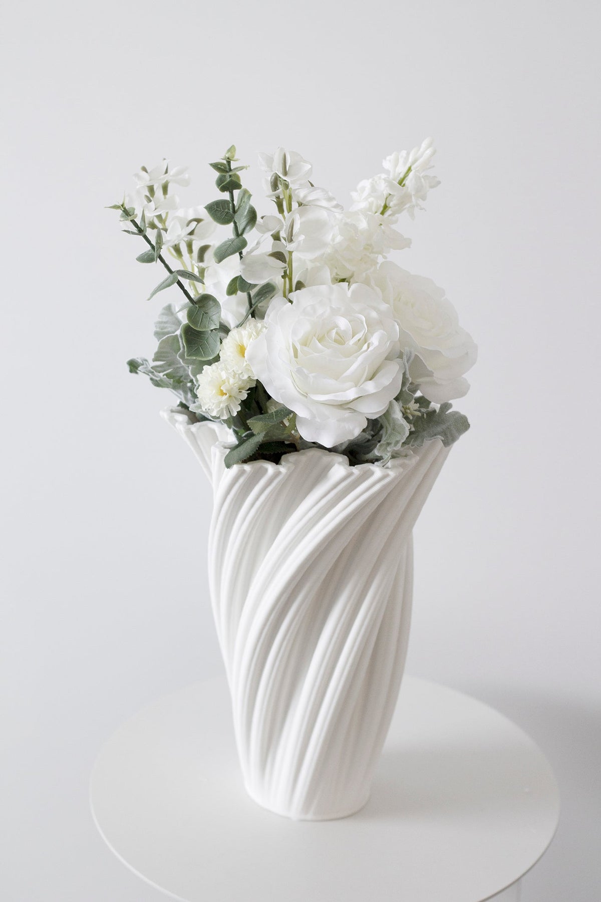 White rose and sweet pea artificial bouquet styled in sculptural white vase
