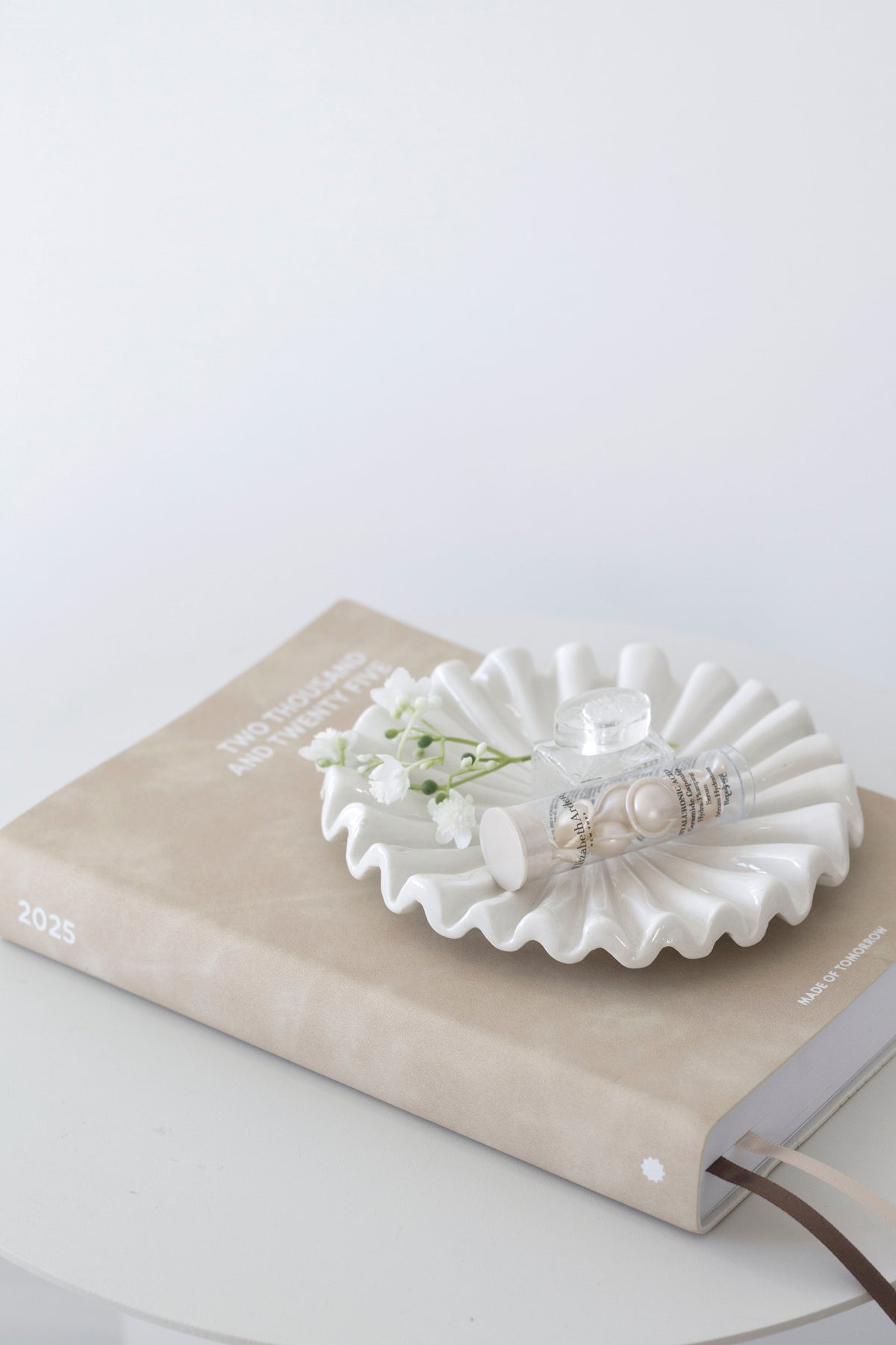 White fluted tray on a book on a round table in soft light