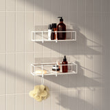A bathroom with two Umbra Cubiko Shower Bins, Set Of 2 hanging on the wall, featuring a bent wire design for shower bin storage and easy adhesive installation.