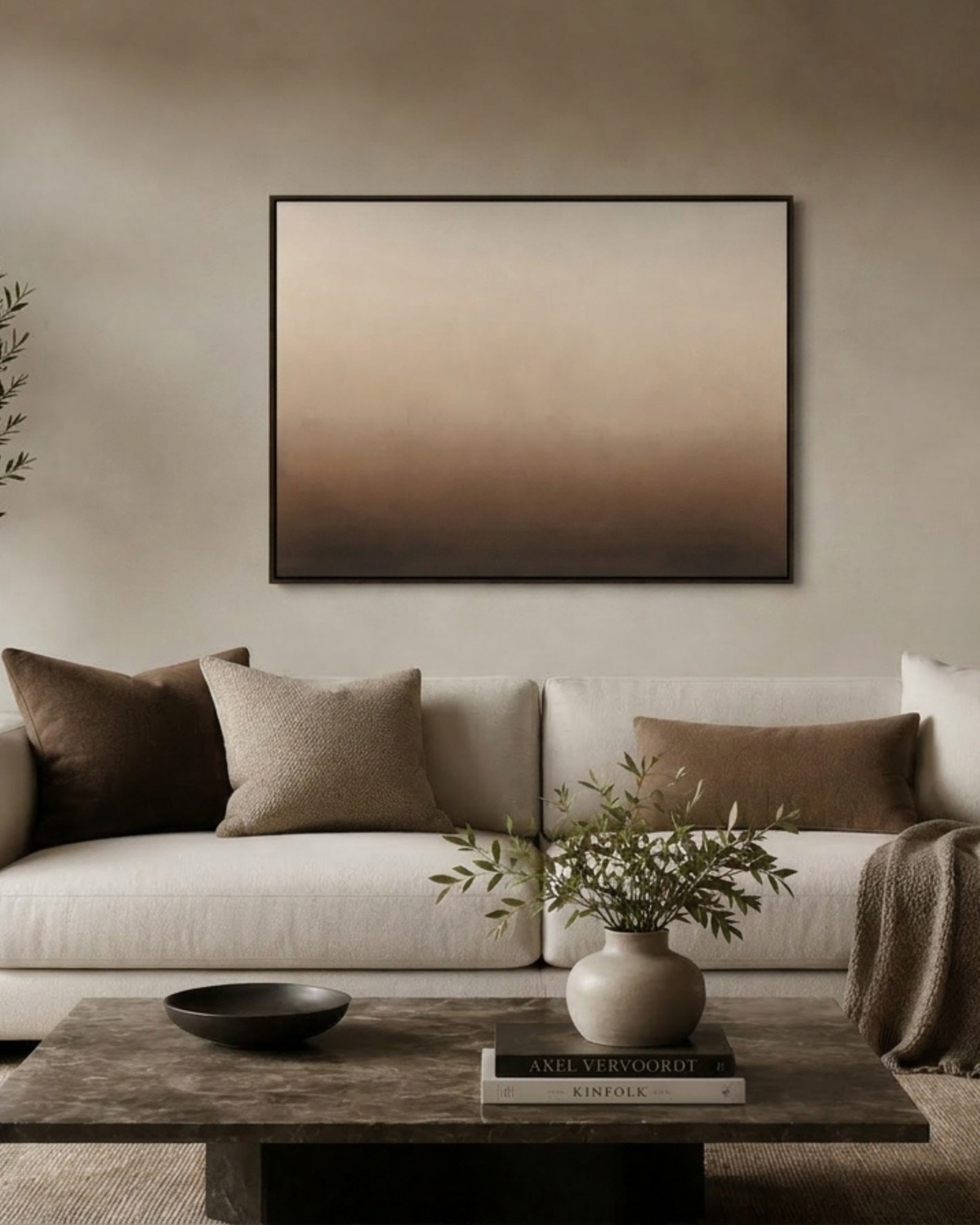 San Viento Landscape Print above a cream sofa with brown cushions, a marble coffee table, black bowl and olive stems