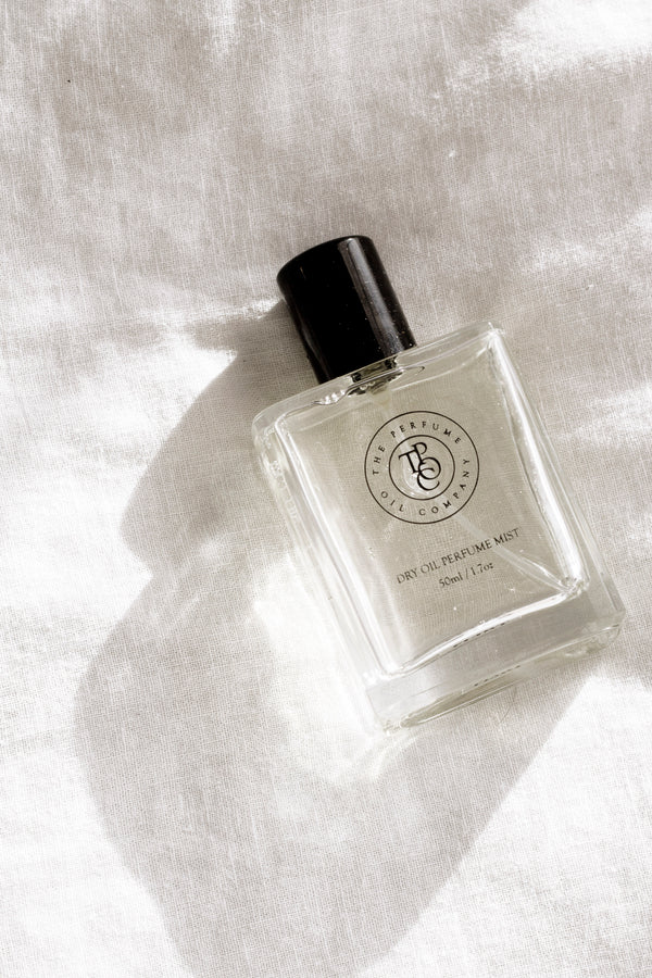 Minimalist fragrance bottle on sunlit linen fabric with soft shadows, clean neutral aesthetic.