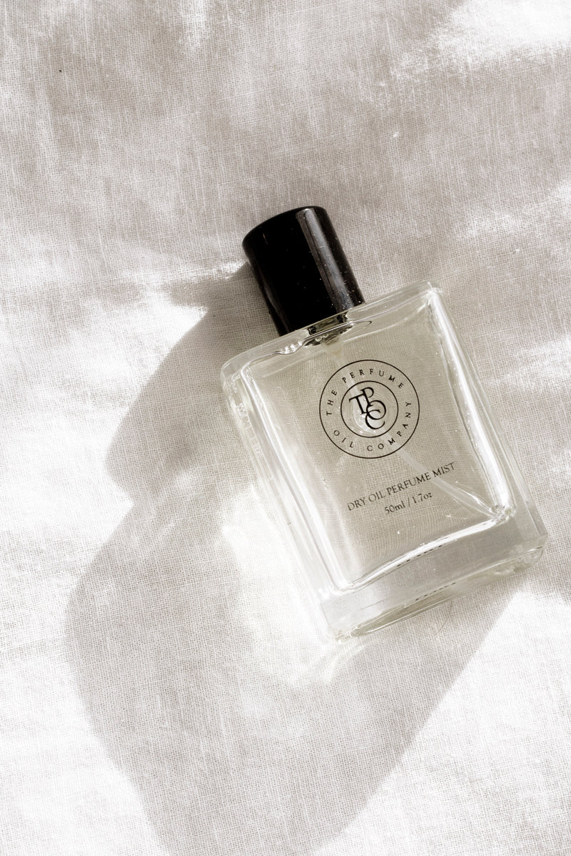 Minimalist fragrance bottle on sunlit linen fabric with soft shadows, clean neutral aesthetic.