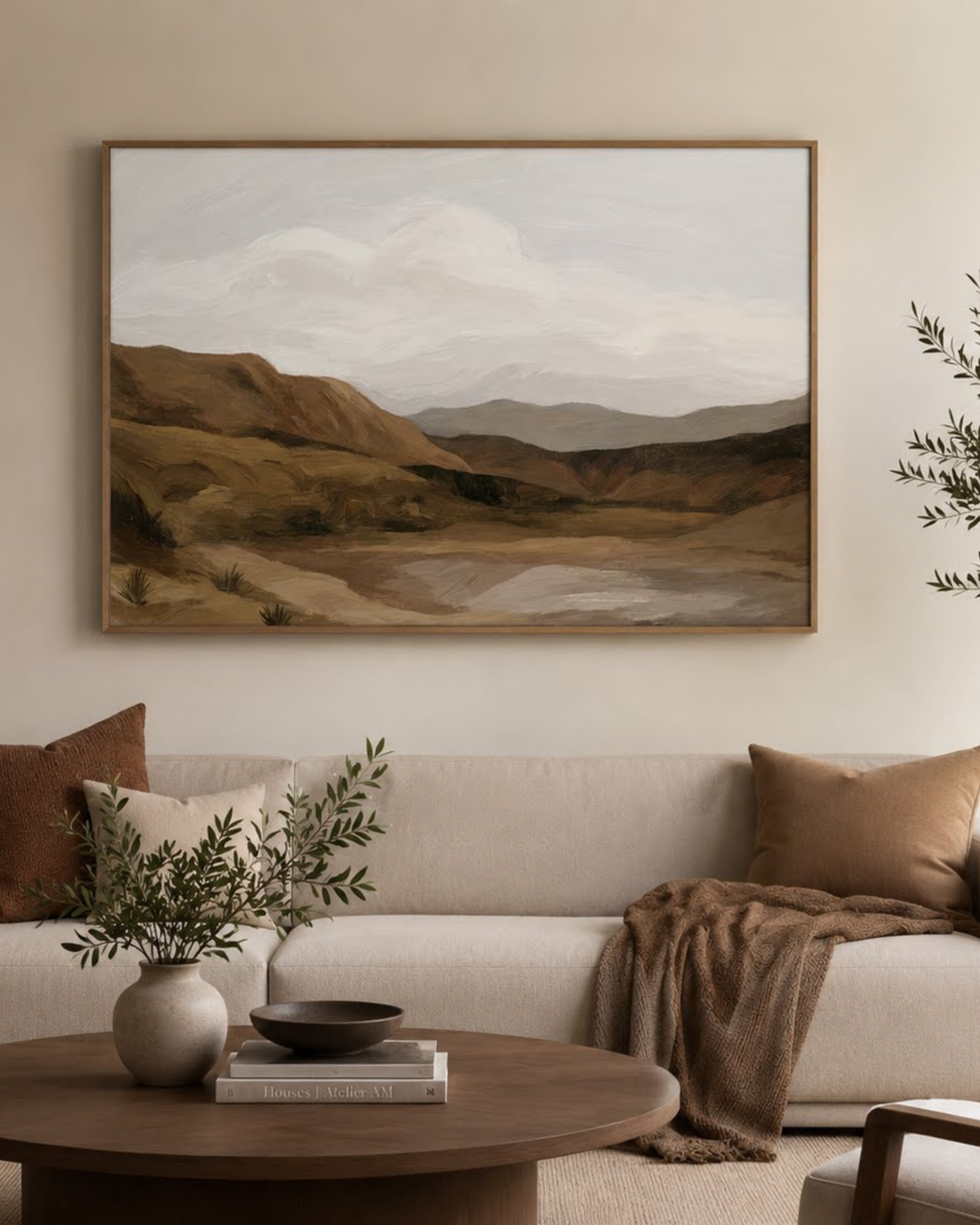 Scout Print above a cream sofa with rust cushions, a round timber coffee table and a vase of olive stems