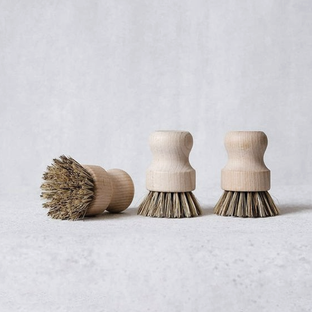 Three pot brushes in a row on pale grey