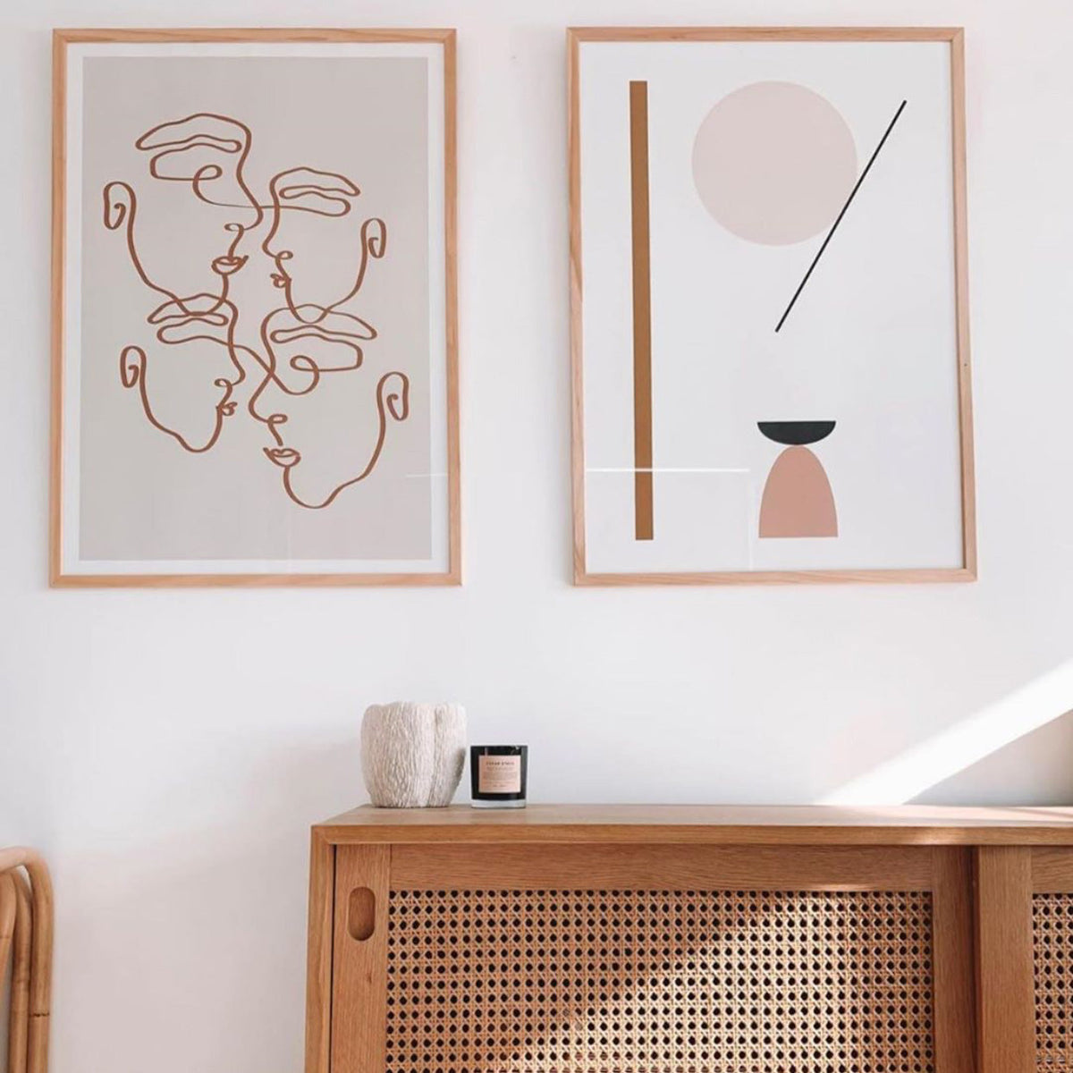 Shape Abstract print in a natural frame beside a line art faces print above a rattan sideboard