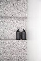 Matte black Smith and Co Tabac Cedar Wood Wash bottles on terrazzo shower shelf